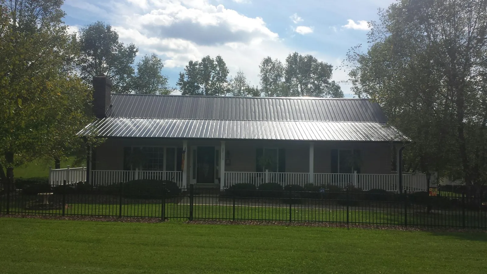 Gray metal roof on a brick ranch with a full width front porch — Gutter Guard Installation work by our crew in Aransas Pass