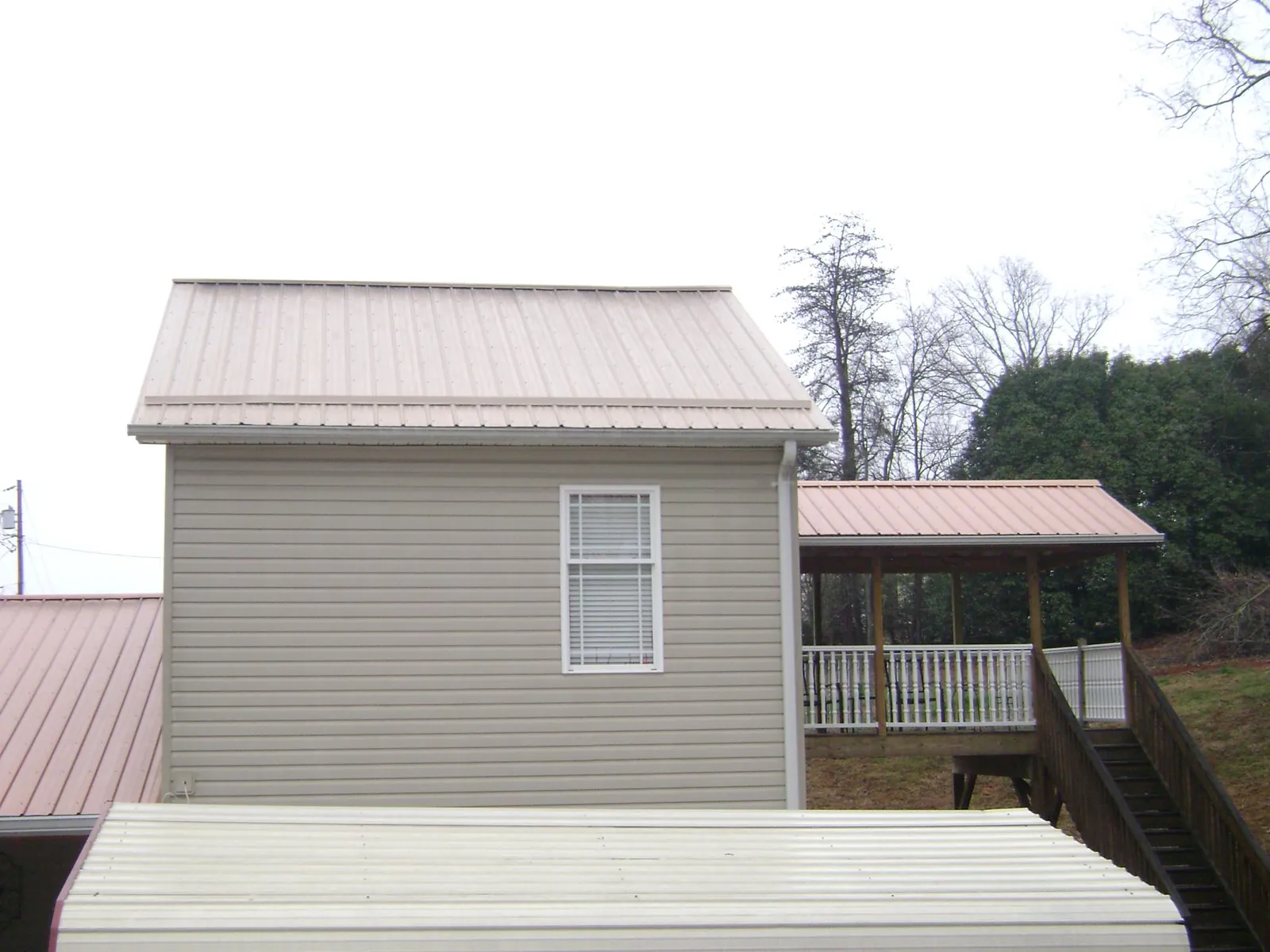 Tan metal roofs on a two story addition and attached porch, from a Roof Replacement job in Aransas Pass