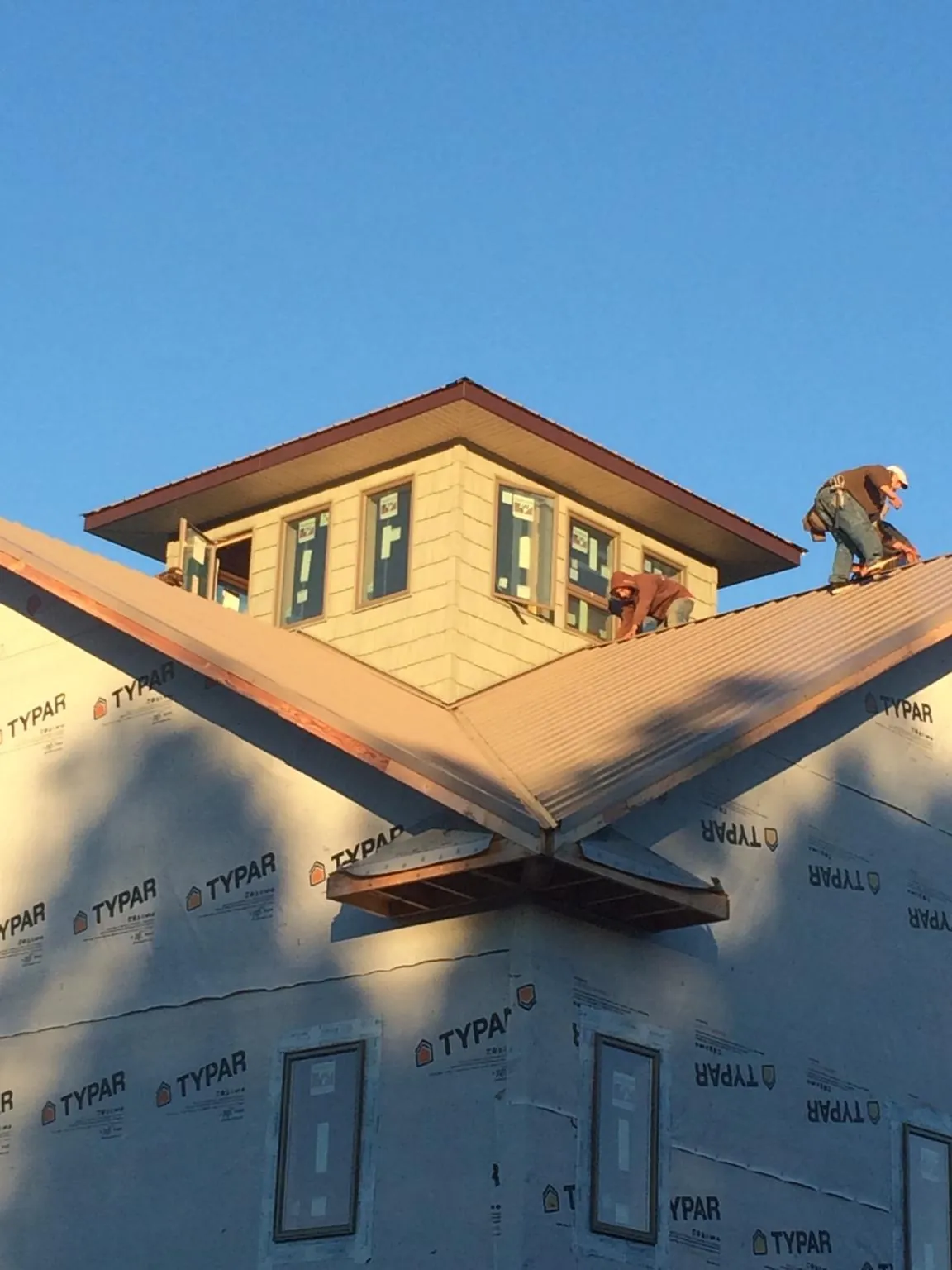 Roofers working around a rooftop cupola on a new metal roof at sunset — Roof Waterproofing in Aransas Pass by Roofing Brothers